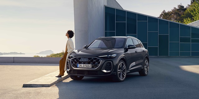 Der Audi Q5 in Front-Seitenansicht mit einer sich am Auto anlehnenden Frau