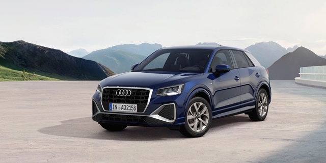 Blauer Audi Q2 in Seitenansicht vor Bergkulisse auf hellem Untergrund