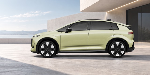 Seitenansicht eines hellgrünen Audi A2 e-tron vor modernem Gebäude mit Bergkulisse im Hintergrund