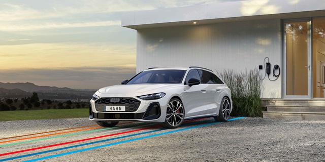 Der Audi A5 Avant eHybrid in weiß und in der Frontansicht vor einem Haus. Unter dem Auto laufen bunte Streifen entlang des Bodens.