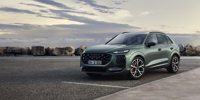 Grüner Audi Q3 in der Seitenansicht auf einem Parkplatz.