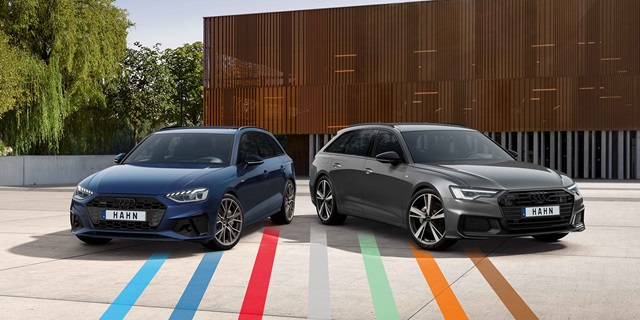 Ein Audi A4 und ein Audi A6 nebeneinander auf einem Parkplatz vor einem modernen Gebäude.