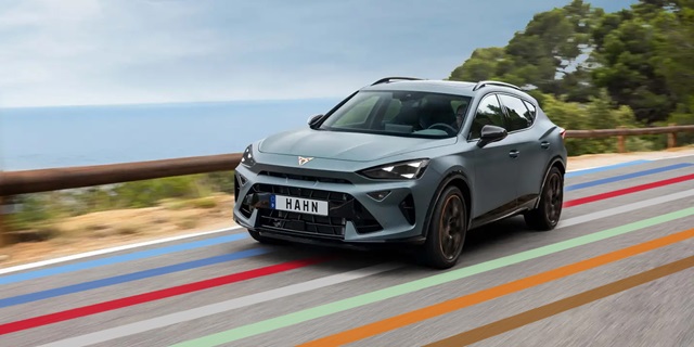 CUPRA Terramar VZ in Frontansicht in Fahrt auf einer Küstenstraße. Auf der Straße sind die bunten Linien des Hahn Codes abgebildet. 