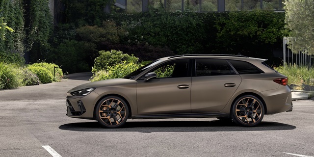 Seitenansicht des braunen CUPRA Leon Sportstourer VZ mit markanten Felgen und sportlicher Karosserie vor begrüntem Hintergrund.