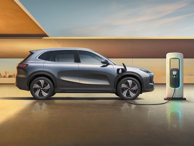 Seitliche Ansicht eines grauen Geely E5, der an einer Ladestation angeschlossen ist