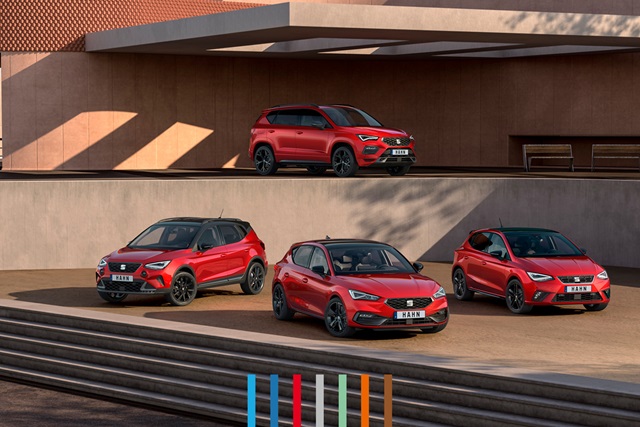 SEAT Leon, SEAT Ateca, SEAT Arona und SEAT Ibiza in rot parkend vor einem modernen Gebäude. Drei der Modelle stehen auf einer Ebene vor einer Wand, ein Modell dahinter etwas erhöht auf einer zweiten Ebene.