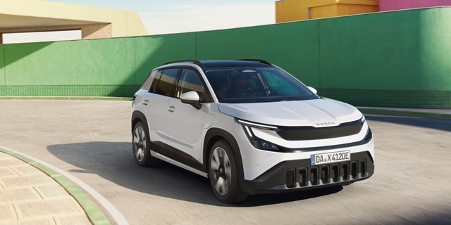 Weißer Škoda Epiq in Frontansicht auf einer Straße vor grüner und gelber Wand.