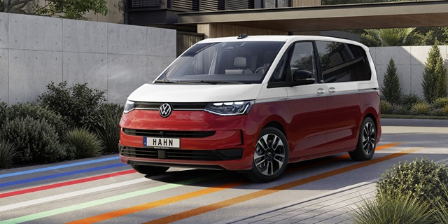 VW Multivan eHybrid in Rot und Weiß als Seitenansicht vor modernem Haus mit Betonfassade und Pflanzen