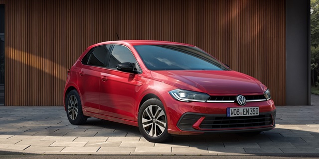Roter Volkswagen Polo ENERGY in Front-Seitenansicht vor einer Holzwand.