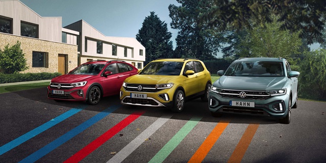Drei verschiedene, bunte Volkswagen-Modelle nebeneinander parkend in einer modernen Umgebung.