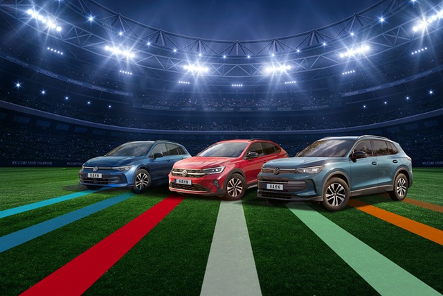 VW Golf Variant, Taigo und Tiguan in Blau, Rot und Grau stehen nebeneinander auf einem Fußballfeld unter Flutlicht in einem Stadion.