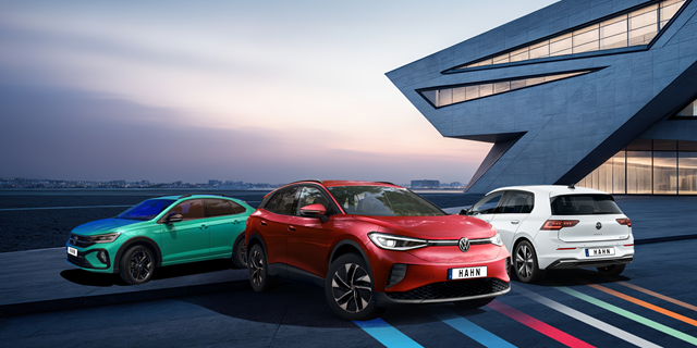 Drei Volkswagen-Fahrzeuge mit einem futuristischen Gebäude im Hintergrund.