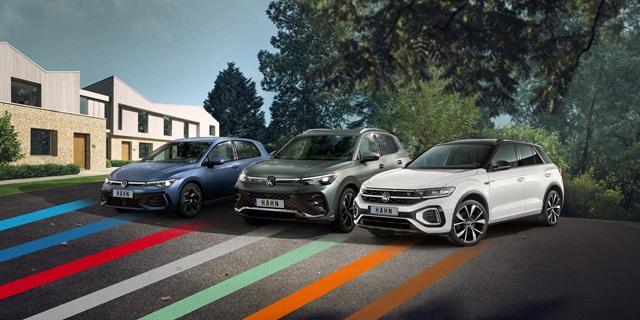 VW Golf, Tiguan und T-Roc nebeneinander geparkt vor modernen Wohnhäusern und Bäumen