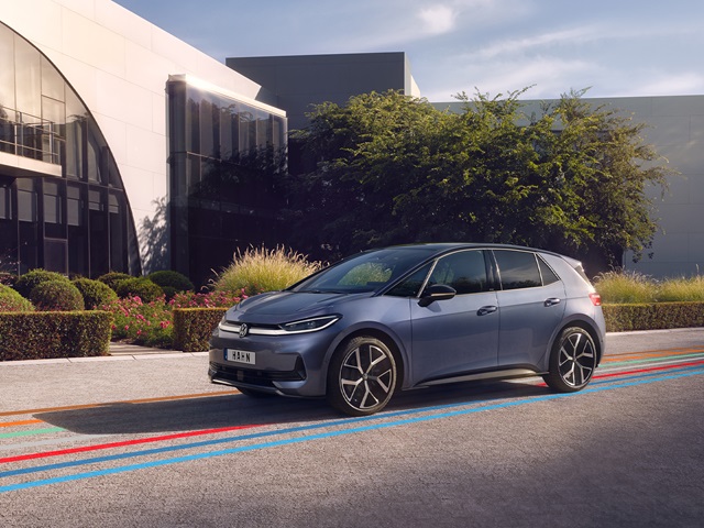 Seitenansicht eines blauen VW ID.3 Neo vor einem modernen Gebäude mit Büschen und Bäumen