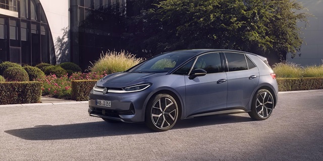 Seitenansicht eines blauen VW ID.3 Neo vor einem modernen Gebäude mit Büschen und Bäumen