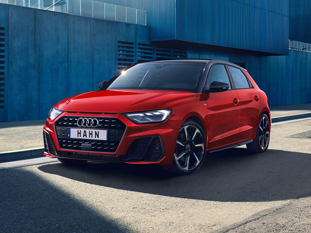 Roter Audi A1 Sportback in Frontansicht vor blauem Gebäude mit schwarzem Dach und markanten LED-Scheinwerfern