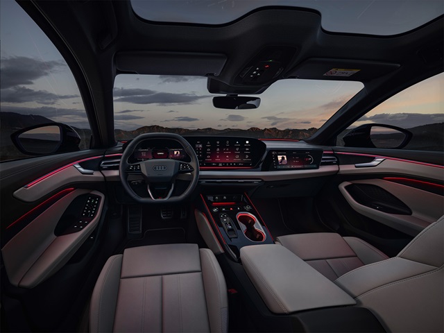 Innenraum des Audi A6 Avant mit digitalem Cockpit, großem zentralem Touchscreen, beleuchteten Türverkleidungen und Panoramadach bei Dämmerung