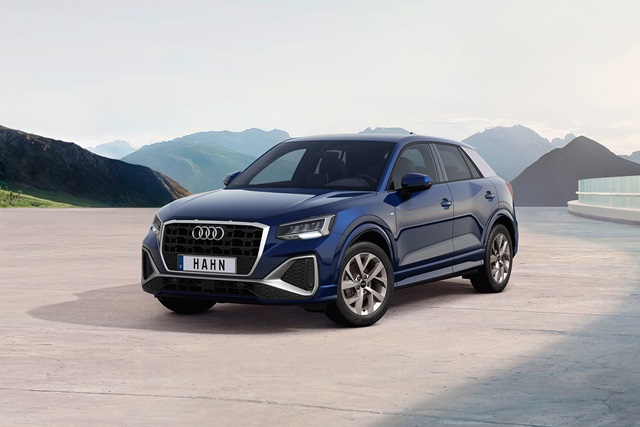 Blauer Audi Q2 in Frontansicht auf hellem Boden vor Bergkulisse