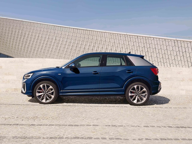 Seitliche Ansicht eines blauen Audi Q2 vor einer hellen, gemusterten Wand