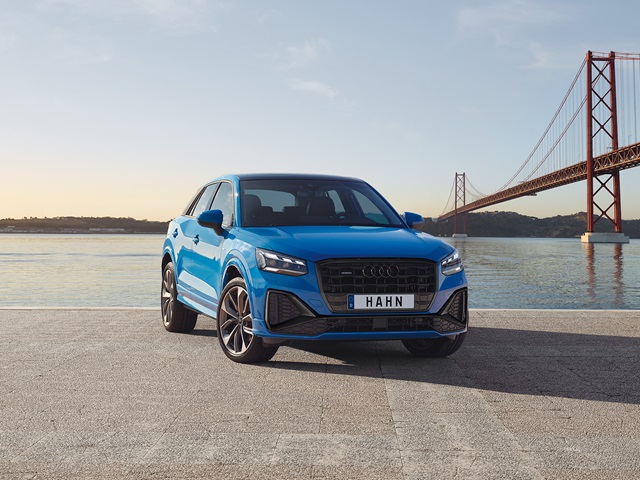 Hellblauer Audi Q2 in Frontansicht auf gepflastertem Platz mit Brücke und Wasser im Hintergrund