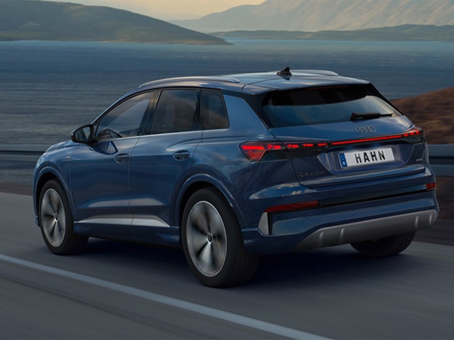 Blauer Audi Q4 e-tron SUV von hinten auf einer Straße mit Berglandschaft im Hintergrund
