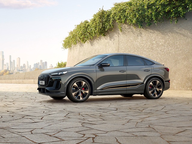 Seitenansicht des Audi Q6 Sportback e-tron in Grau, modernem Design, auf Steinboden mit urbanem Hintergrund.