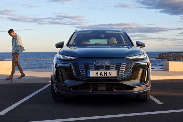Frontansicht des Audi Q6 SUV e-tron mit modernem Design, am Hafenparkplatz, im Hintergrund das Meer und der Himmel.