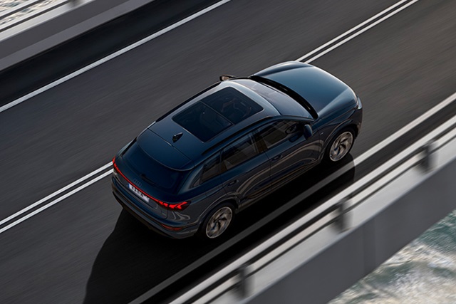 Obenansicht des blauen Audi Q6 SUV e-tron auf einer Küstenstraße mit modernen Linien und Panoramadach.