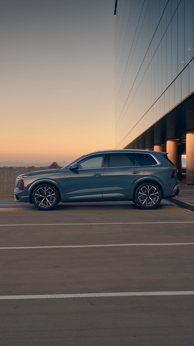 Seitenansicht eines blauen Audi Q7 SUV auf einem Parkplatz mit Brückenpfeilern im Hintergrund