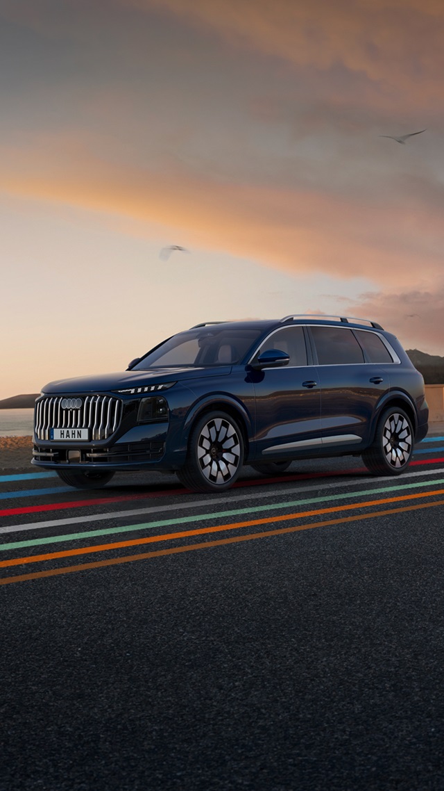 Seitenansicht eines blauen Audi Q9 SUV auf einer Straße mit farbigen Linien und einem Himmel bei Sonnenuntergang