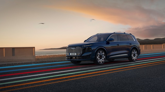Seitenansicht eines blauen Audi Q9 SUV auf einer Straße mit farbigen Linien und einem Himmel bei Sonnenuntergang