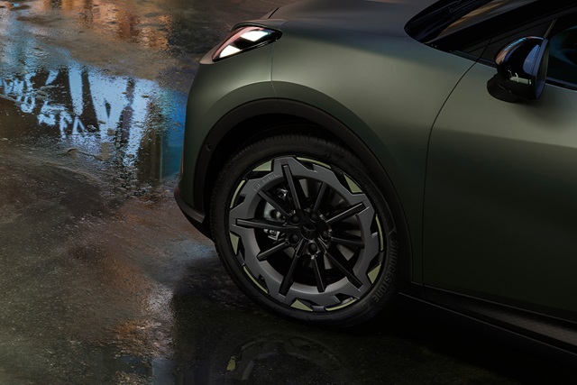 Nahaufnahme des vorderen linken Rads eines CUPRA Raval in manganese matt mit markantem Felgendesign und Reifenprofil auf nassem Asphalt.