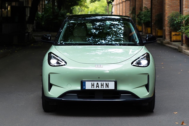 Mintgrüner Geely E2 in Frontansicht mit sichtbarem Kennzeichen 'HAHN' auf einer Straße