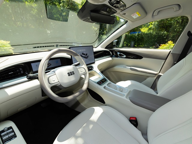 Innenraum des Geely E2 mit hellen Bezügen und Armaturen sowie digital Cockpit und Bildschirm