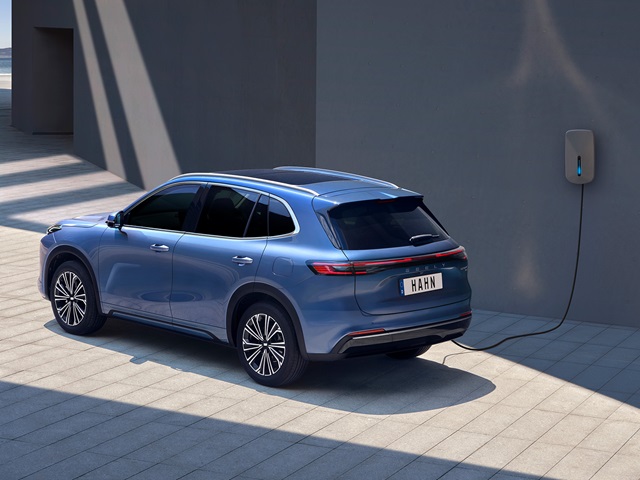 Blauer Geely Starray EM-i beim Laden an einer Wandladestation mit Kabelanschluss und Kennzeichen 'HAHN'