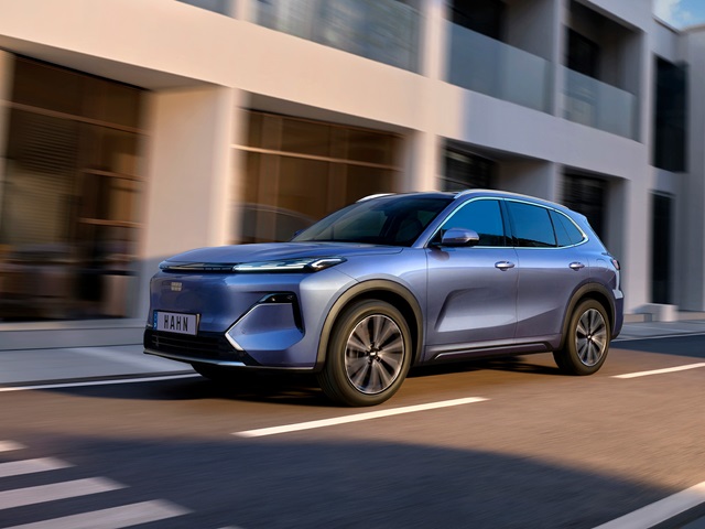 Geely Starray EM-i in blauer Seitenansicht fahrend vor modernem Gebäude