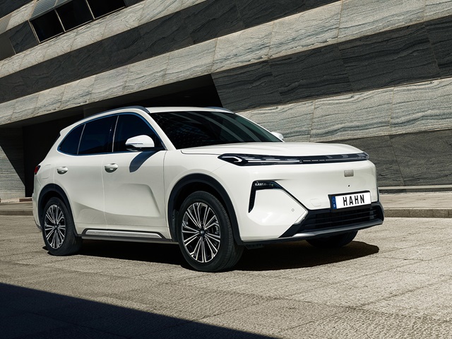 Weiße Seitenansicht des Geely Starray EM-i vor einer modernen, gestreiften Steinwand mit schwarzem Kühlergrill und schmalen Scheinwerfern
