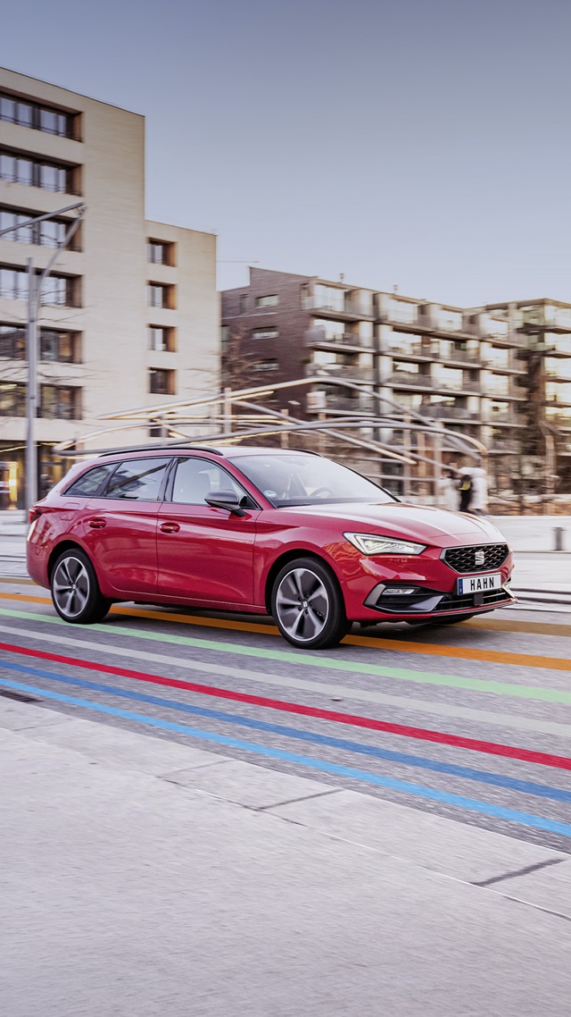 Roter SEAT Leon Sportstourer in Seitenansicht auf einer Straße mit farbigen Linien im urbanen Umfeld