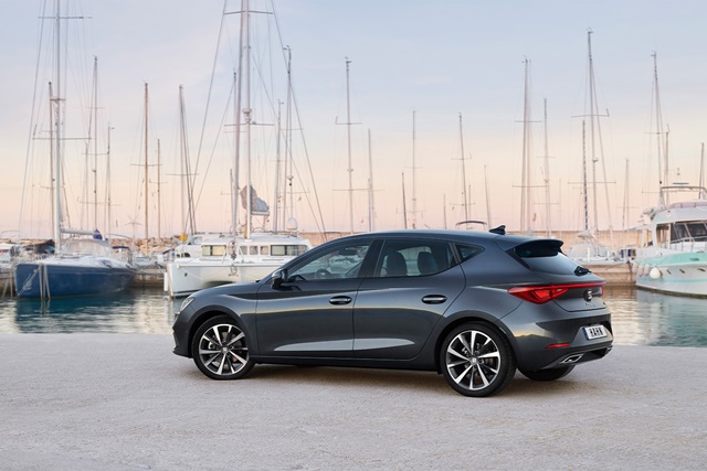 Seitliche Ansicht eines grauen SEAT Leon vor einem Hafen mit mehreren Segelbooten im Hintergrund