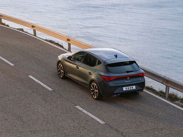 SEAT Leon in Grau aus der Vogelperspektive auf einer Küstenstraße mit Geländer und Wasser im Hintergrund