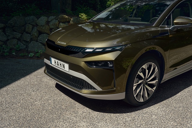 Nahaufnahme der Frontpartie eines grünen Škoda Enyaq mit markantem Scheinwerferdesign und Kennzeichen 'HAHN'