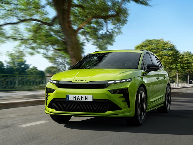 Grüner Skoda Enyaq RS in der Frontansicht fährt auf einer Straße und im Hintergrund Bäume
