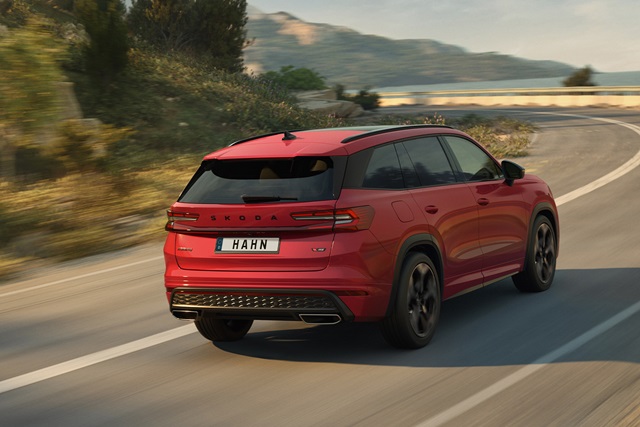 Roter Škoda Kodiaq RS in der Rückansicht fährt auf kurviger Straße mit Berglandschaft im Hintergrund