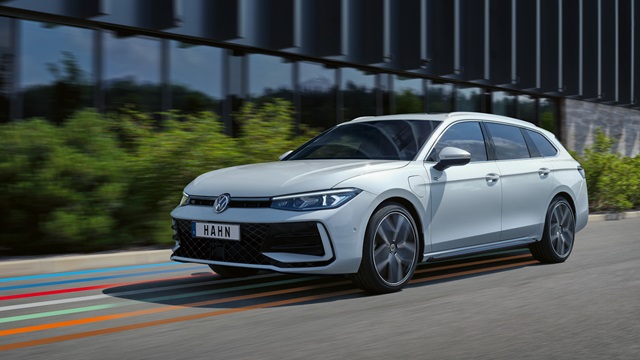 Weißer VW Passat R-Line Kombi in Seitenansicht mit markanten Felgen und sichtbarem Kühlergrill vor einem modernen Gebäude