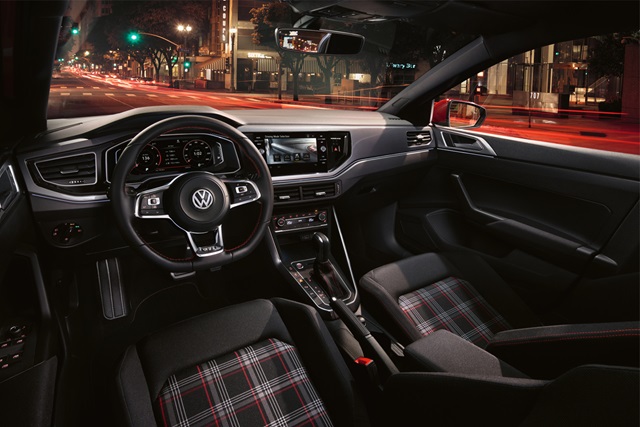 Innenraum des VW Polo GTI mit sportlichem Lenkrad, digitalem Cockpit, Touchscreen-Mittelkonsole und Sitzen mit Karomuster