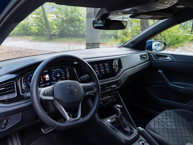 Innenraum eines VW Polo mit digitalem Cockpit, Multifunktionslenkrad, Touchscreen-Mittelkonsole und Stoffpolstern mit Rautenmuster
