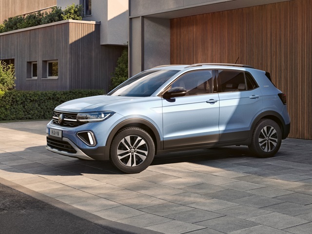 VW T-Cross in hellblauer Lackierung aus seitlicher Perspektive vor einem modernen Gebäude