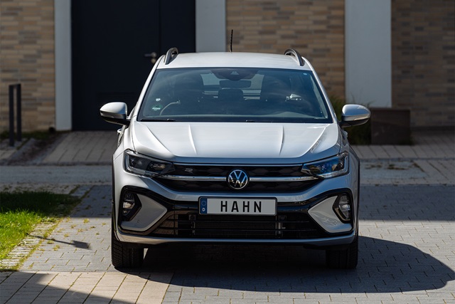 Frontansicht eines silbernen VW Taigo R-Line mit deutschem Kennzeichen 'HAHN' vor einem Gebäude