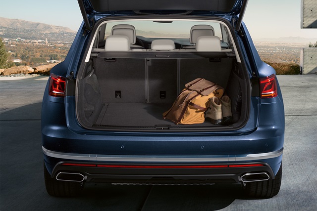 Offener Kofferraum eines blauen VW Touareg mit einer braunen Reisetasche und einem Paar Stiefel darin