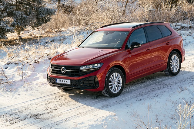 Roter VW Touareg R-Line steht seitlich auf verschneitem Weg vor winterlicher Landschaft